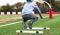 Male athlete jumping over a track hurdles on a turf field Royalty Free Stock Photo