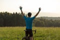 Male cyclist riding a bike with arms raised, in a victory pose