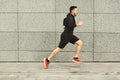 Male athlete running in city against grey wall Royalty Free Stock Photo