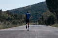 Male athlete running on an empty road in the woods while trying to get to the red finish line