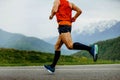 male athlete running mountain marathon on asphalt