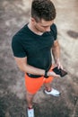 A male athlete, summer city on sports field, holds phone in his hand, a choice of Internet applications, online training Royalty Free Stock Photo