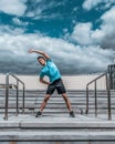 Male athlete, in summer spring in city heats up muscles of arms of back and torso, before gymnastics jogging. Active Royalty Free Stock Photo