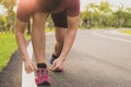 The male athlete is tying running shoes in the park with sunlight. Sport and exercise concept Royalty Free Stock Photo