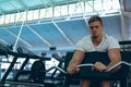 Male athletic exercising with barbell on preacher bench in fitness center