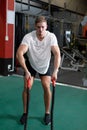 Male athletic exercising with battle ropes in fitness center