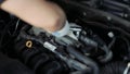 Male auto mechanic changes spark plugs in a car engine