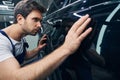 Male auto mechanic inspecting surface of car