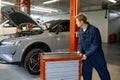 Male auto mechanic pushing wheeled tool kit box at car repair service station Royalty Free Stock Photo