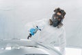 Male auto painter in protective mask and suit painting automobile car bumper in chamber. Royalty Free Stock Photo