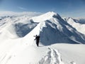 Male back country skier carrying his skis along a narrow snow ridge