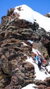 Male back country skier climbing to a exposed rocky summit with his skis strapped to his backpack