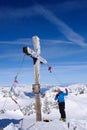 Male backcountry skier at the summit cross of a high alpine peak on a beautiful winter day