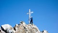 Male backcountry skier at the summit cross of a high alpine peak on a beautiful winter day