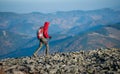 Male backpaker walking on the rocky top of the mountain