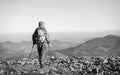 Male backpaker walking on the rocky top of the mountain