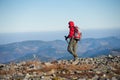 Male backpaker walking on the rocky top of the mountain