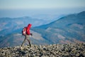 Male backpaker walking on the rocky top of the mountain