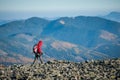 Male backpaker walking on the rocky top of the mountain