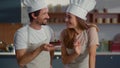 Baker and assistant putting cherry on cake at kitchen. Couple of confectioners