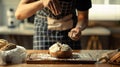 Male baker wearing apron sifting flour on dough, making bread in kitchen Royalty Free Stock Photo