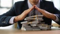 Male banker protecting with hands lot of banknotes closeup