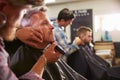 Male Barber Giving Client Shave In Shop