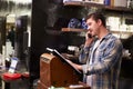 Male Barber Standing By Cash Register Taking Booking