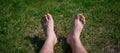 Male bare feet on a lawn in a park on a hot sunny summer day. A man lies on the grass green grass without shoes. Cropped Royalty Free Stock Photo