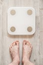 Male bare feet stand next to smart scales that makes bioelectric impedance analysis, BIA, body fat measurement. Top view Royalty Free Stock Photo