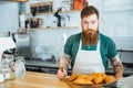 Male barista with beard and tattoo standing in coffe shop