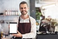 Male barista holding and showing a digital tablet