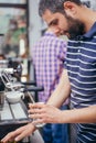 Male barista making cappuccino at counter in coffeeshop Royalty Free Stock Photo