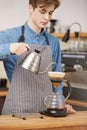 Male barista pouring water through grounds making pourover coffee. Royalty Free Stock Photo