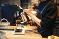 Male barista pours boiling water into the glass