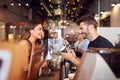 Male Barista Writing Female Customers Name On Cup In Coffee Shop