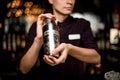 Male bartender holding in hands a steel shaker with a deliciouds cocktail