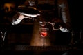 Bartender pours cocktail with sieve in glass