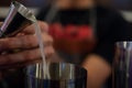 A male bartender prepares a bright alcoholic cocktail from a steel shaker into a glass. close-up view. Bartender mixing Royalty Free Stock Photo
