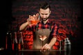 Male bartender pours cocktail from mixing cup into metal martini glass.