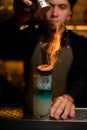 Male bartender sprinkling fired up blue alcohol drink with feijoa