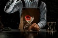 Male bartender throwing a big red rose bud to a martini glass with a alcoholic cocktail Royalty Free Stock Photo
