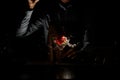 Male bartender throwing a red rose bud to a martini glass with a cocktail in the dark Royalty Free Stock Photo
