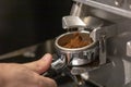 Male bartender on the workplace. Closeup image of male hands while making coffee using coffeegrinder and coffeemachine