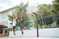 a male basketball player takes a jump shot and is blocked by his opponent with both hands