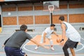 a male basketball player in a white tracksuit dribbles the ball in the face of two opposing players Royalty Free Stock Photo