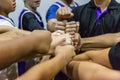 Male basketball players and their coach putting their fists toge