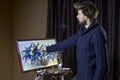 Male bearded artist in a dark sweater draws an artistic brush painting flowers still life in studio