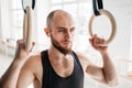 Male bearded athlete resting and holding gymnastics rings at light gym Royalty Free Stock Photo