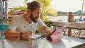 Male designer draw sketches in open air riverside cafe.